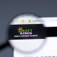 A magnifying glass enlarges the DraftKings’ name and logo from a website browser