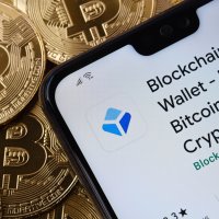 Blockchain.com Wallet app seen on smartphone screen placed on top bitcoin coins