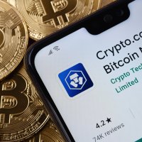 Crypto.com app seen on the smartphone screen placed on top of a pile of bitcoins