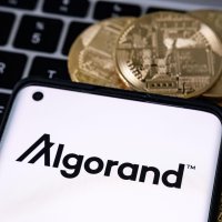 Algorand’s logo appears on a smartphone, which is lying down on a laptop keyboard.
