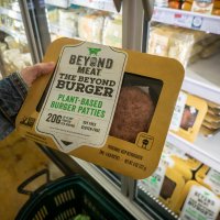 A shopper picks out two Beyond Meat burgers out of a fridge in a supermarket. 