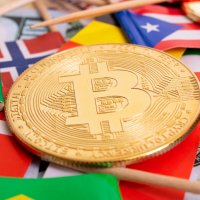 A bitcoin lies on top of flags from different countries