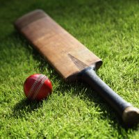 A cricket bat and ball lie on turf