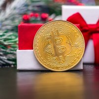 A bitcoin in front of a white and red gift box