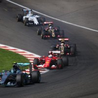 Formula 1 cars hug a bend in single file at a Grand Prix race
