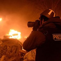 A press photographer taking a photo of a collapsed, burning building