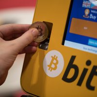Someone pretends to insert a physical bitcoin into a bitcoin ATM