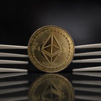Ethereum Classic cryptocurrency physical coin placed between two plastic forks in the black background