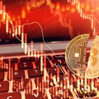 Image of a bitcoin split in half, foregrounding a red bearish stock chart and keyboard – Photo: Shutterstock
