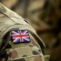 Anonymous close-up of a British Army personnel's arm, showing camouflage uniform and the Union flag badge 