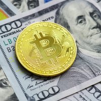 Representation of a golden bitcoin lying flat on a $100 bill