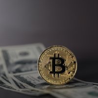 Bitcoin on top of US hundred-dollar bills