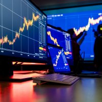Analysts examine market charts on a wallscreen