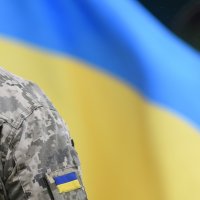A soldier looking at the Ukrainian flag