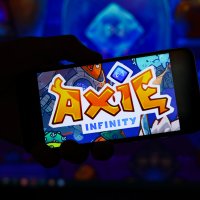 Axie Infinity's cartoon logo shown on a smartphone screen in the dark