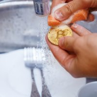 A bitcoin being washed in a sink under running water