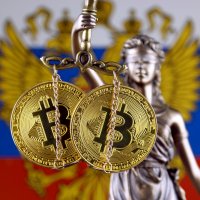 Two bitcoins hanging from a chain in front a Russian flag