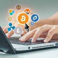 A laptop with different cryptocurrency logos floating above the keyboard