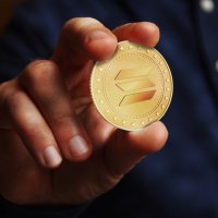  A hand holding a golden SOL coin