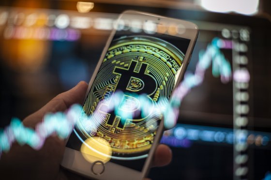 An Apple iPhone displays a Bitcoin overlaid by a trading chart