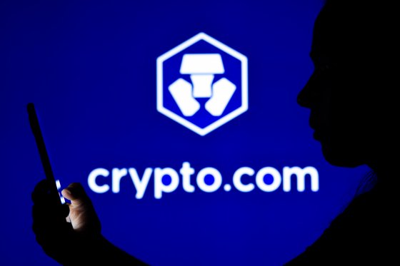 Illustration of a woman's silhouette holding a smartphone in front of the Crypto.com logo