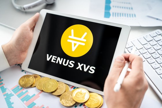 A computer tablet displays the Venus XVS name and logo above a collection of cryptos