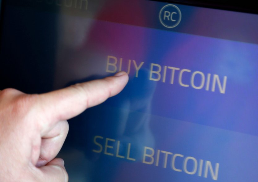 A finger touches the words Buy Bitcoin on a Bitcoin ATM