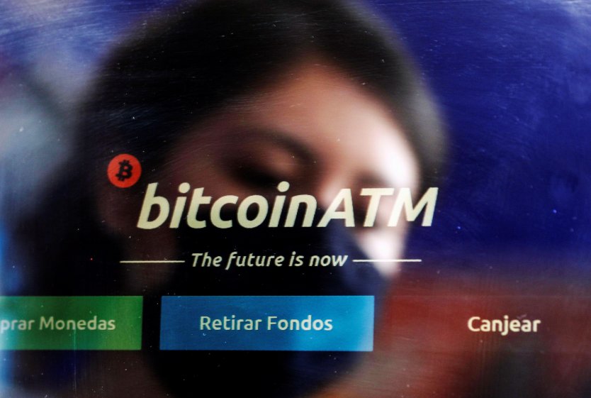 An employee is reflected as she cleans the screen of a bitcoin ATM in a shop in Mexico City