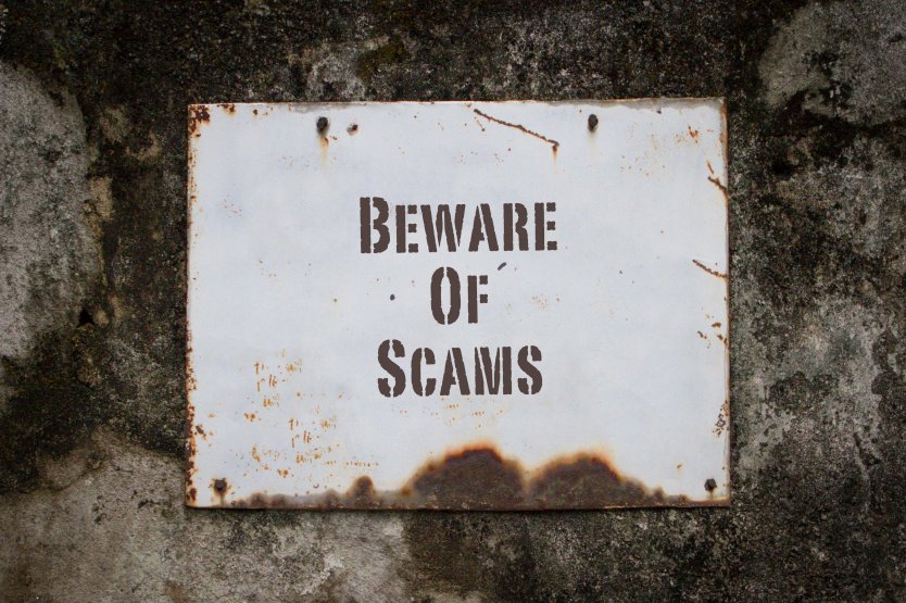 Beware of scams, words on a worn out white board