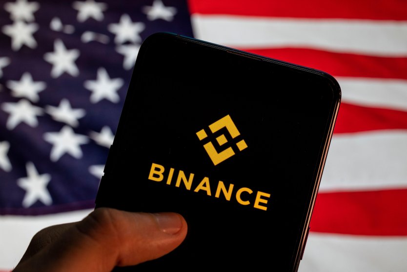 Binance logo on a mobile device with US flag in the background