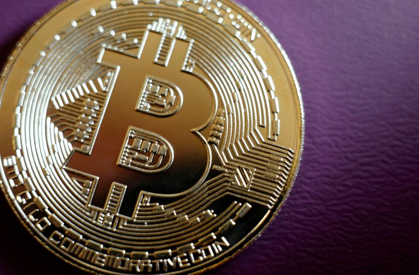 Gold plated bitcoin coin on purple background 