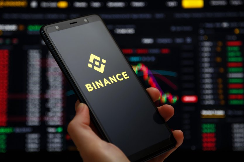Binance mobile app running on a smartphone screen with a trading page at background