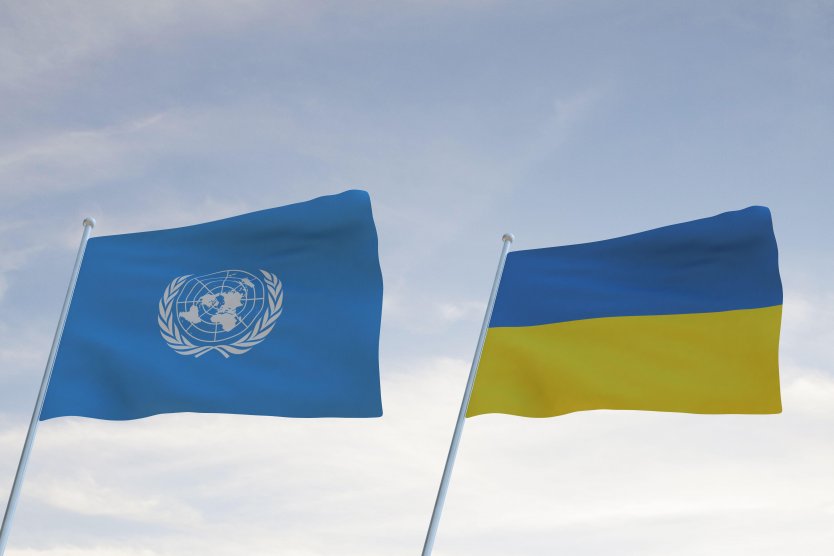 Flags of UN and Ukraine waving with cloudy blue sky background