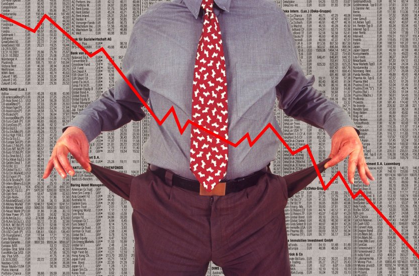 A man holding out empty pockets in front of a trading chart