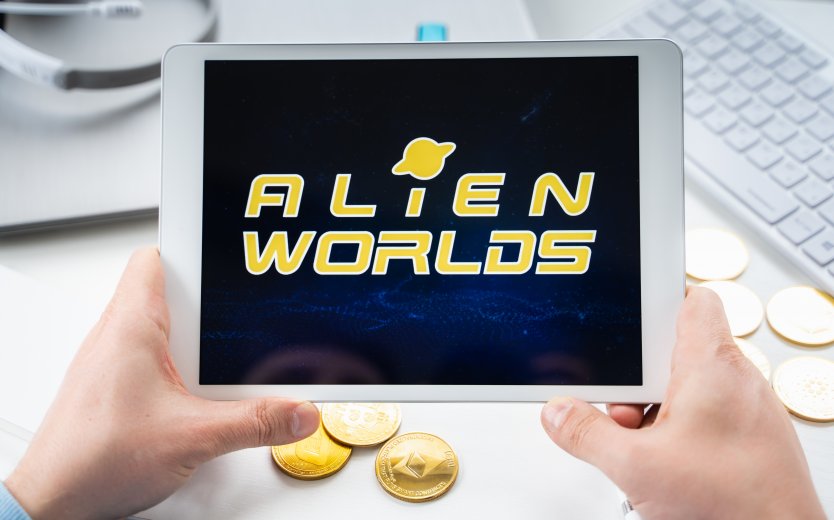 Alien Worlds’ company name and logo displayed in yellow lettering on a computer tablet