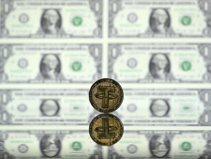 Representation of a Tether token standing on a mirror in front one dollar bills