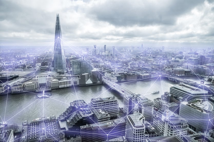 Graphic representation of a city connected by blockchain technology, showing London's Shard connected to other buildings by digital lines of communication