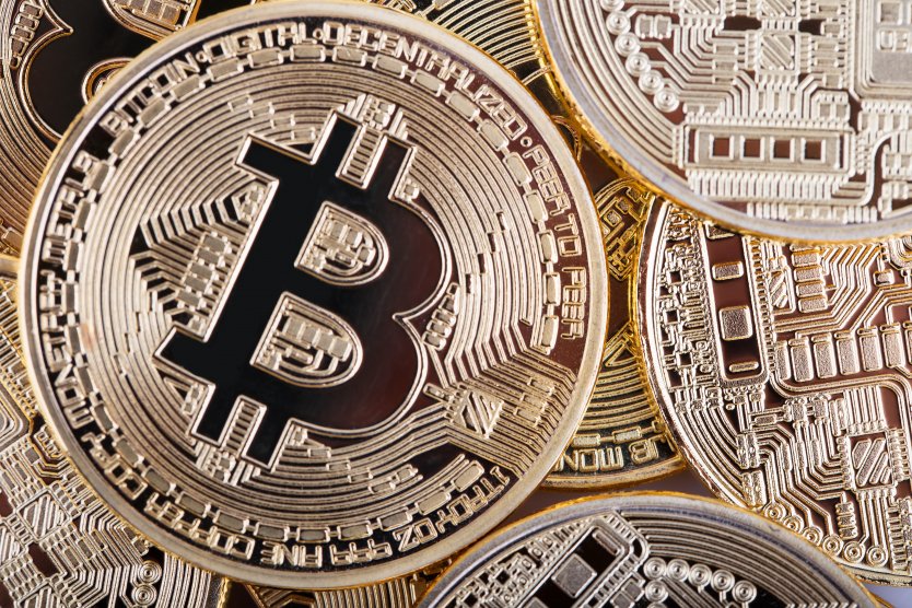 Representation of a bitcoin lying on a pile of golden crypto coins