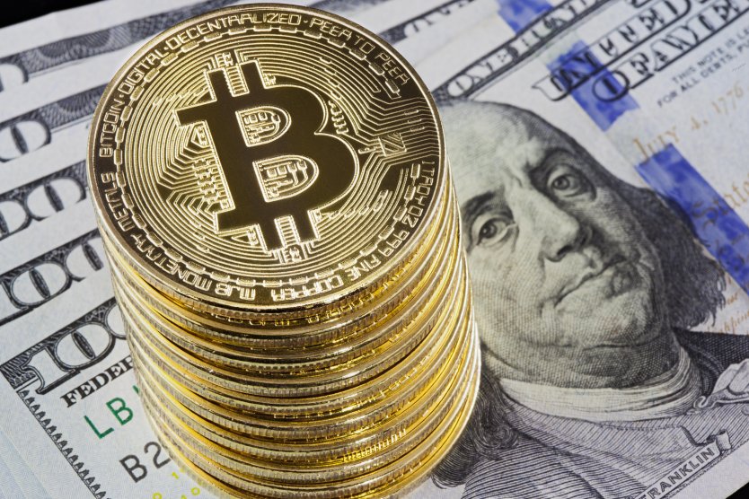 Golden bitcoin coins on $100 bills background