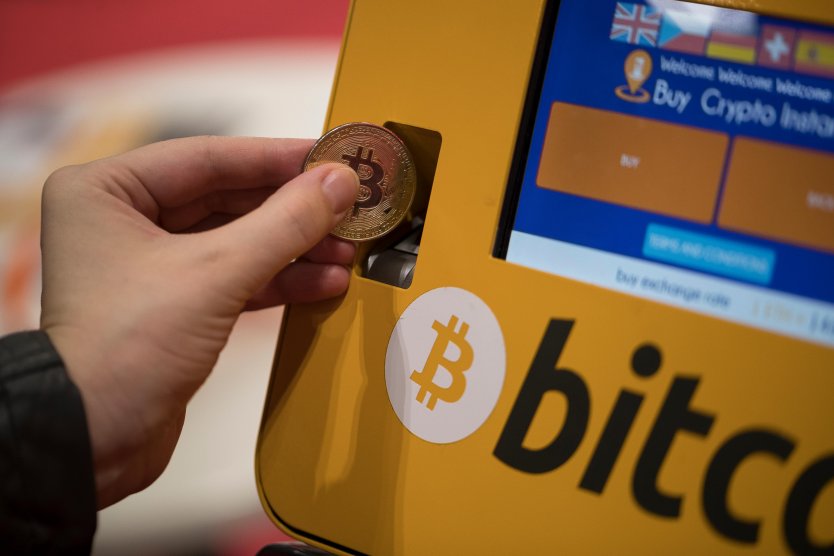 Someone pretends to insert a physical bitcoin into a bitcoin ATM