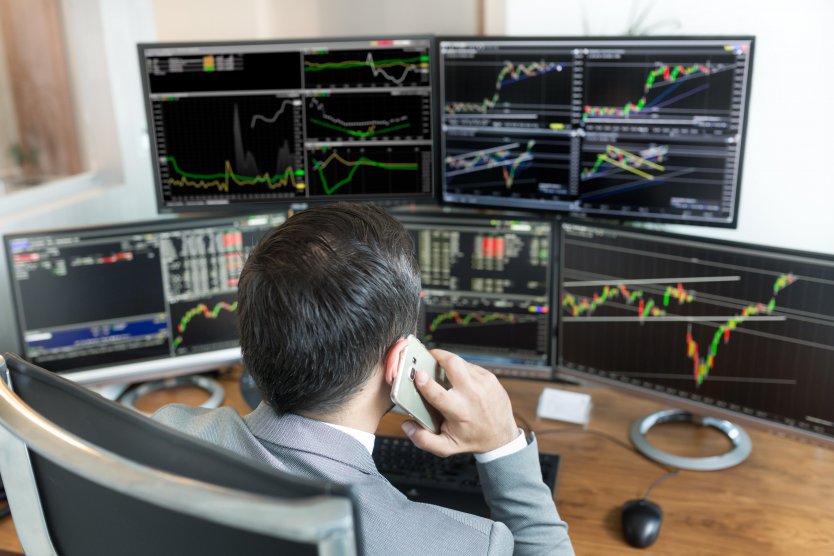 A trader studies screens that include charts and stock prices