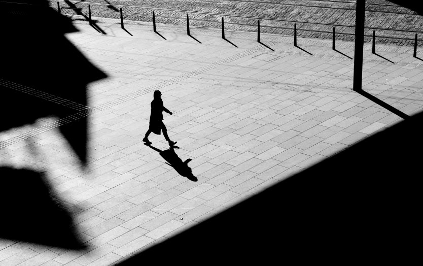 Black and white photo of a woman walking in shadows 