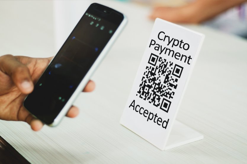 Using a smartphone to access a QR code alongside a message that crypto payments are accepted