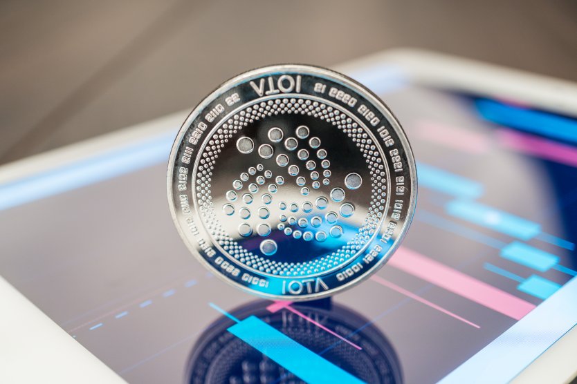 Iota coin standing on a digital device