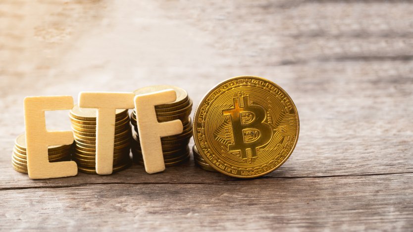 A representative golden bitcoin token stands next to more coins and the letters ETF 