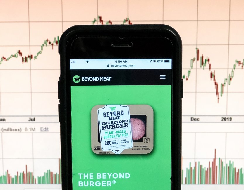 Beyond Meat website on a smartphone with stock chart visible in the back