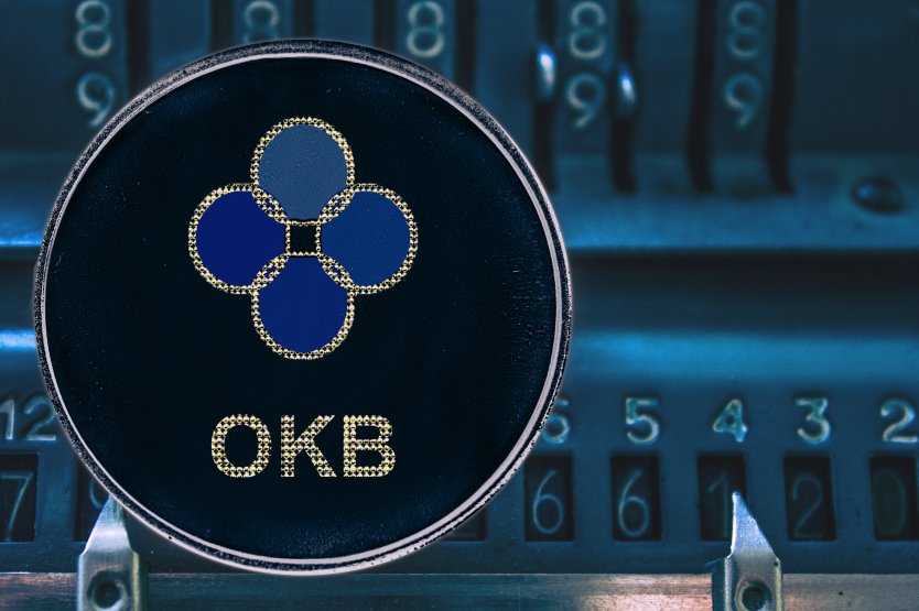 The blue logo of OKB on a black disc with an old-fashioned code machine in the background