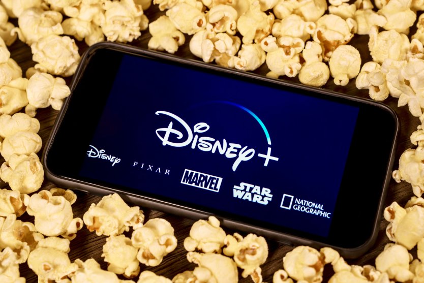 Disney+ screen on smartphone surrounded by popcorn