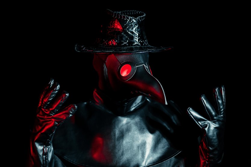 Portrait of plague doctor, red eyes, black hat – Photo: Shutterstock