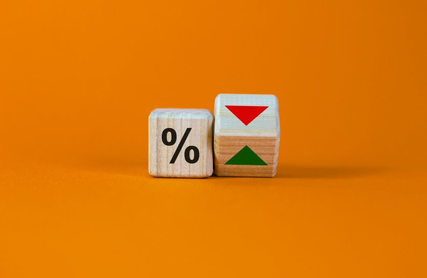 Two wooden dice, one with percentage sign, the other with an up arrow and a down arrow – Photo: Shutterstock